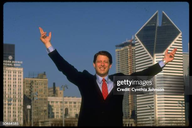 Sen. Al Gore raising arms triumphantly, framed by Chicago skyline, on road, campaigning for Dem. Presidential nomination.