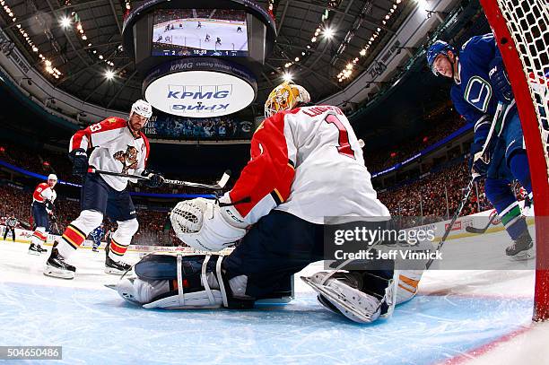 Willie Mitchell of the Florida Panthers and Radim Vrbata of the Vancouver Canucks look on as Roberto Luongo of the Florida Panthers makes a save...