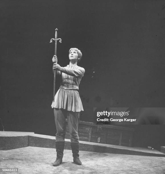 Actress Julie Harris holding sword in front of her on stage, in role as Joan of Arc.