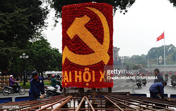 Workers install a decoration with a large hammer and sickle, marking the up-coming Vietnam Communist Party's national congress, near to the mausoleum...