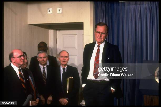 Pres. Bush striking pensive lip-biting stance, in WH Press Rm. W. Attentive aides Fitzwater, Sununu, Gates & Scowcroft.