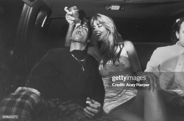 Rap star Vanilla Ice having honey poured down his throat by model Rowanne Brewer in the back of a limo.