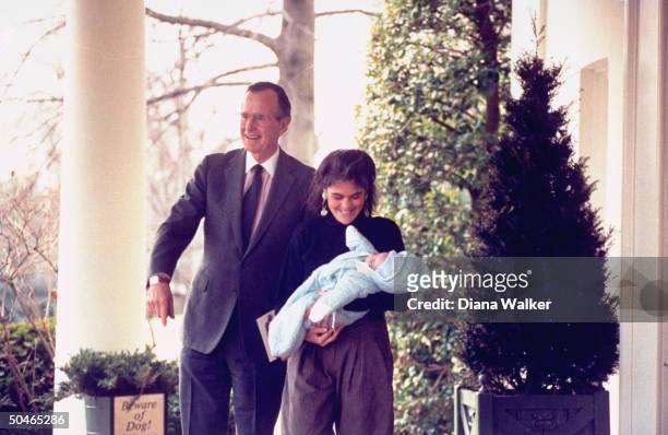 Beaming grandpa Pres. Bush standing by beware of dog! sign-bearing planter, w. Babe-in-arms bearing daughter-in-law Margaret , by WH portico.
