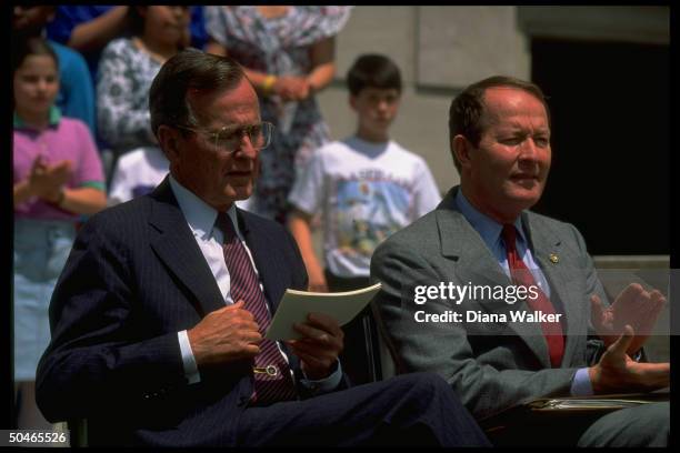 Pres. Bush sitting outside w. Education Secy. Lamar Alexander , framed by kids, during fete at St. Paul Public Library .