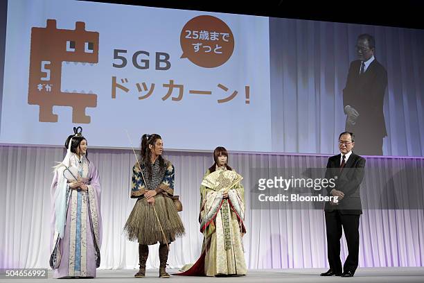 Takashi Tanaka, president of KDDI Corp., right, speaks while model and actress Nanao, from left, actor Kenta Kiritani and actress Kasumi Arimura look...