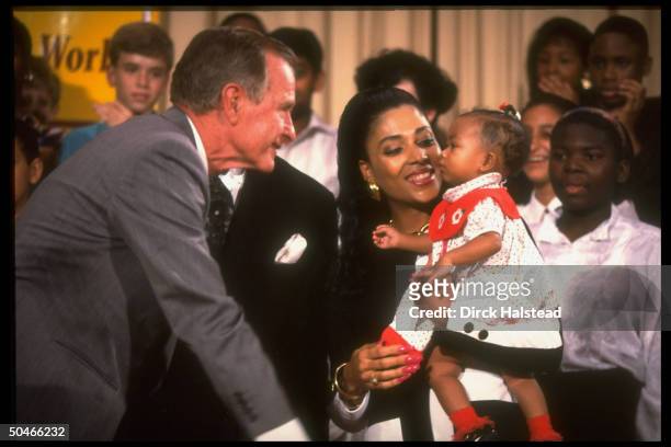 Pres. Bush w. Track star mom Flo Jo Griffith Joyner, cooing at baby Mary, paying call at Alice Deal Jr. HS.