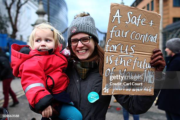 Junior doctor holds her baby and a placard as she takes part in a picket outside Kings College Hospital on January 12, 2016 in London, United...