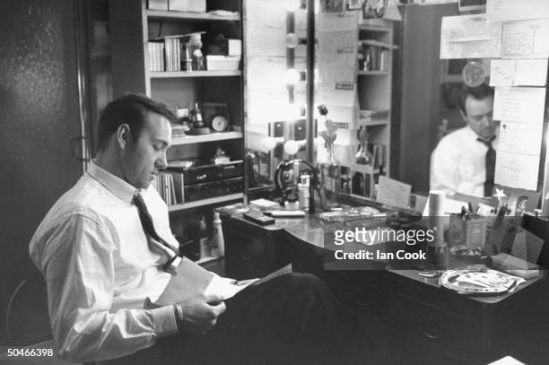 Actor Kevin Spacey reading letter as he sits at table in front of mirror in his dressing room at the Richard Rodgers Theater where is performing in...