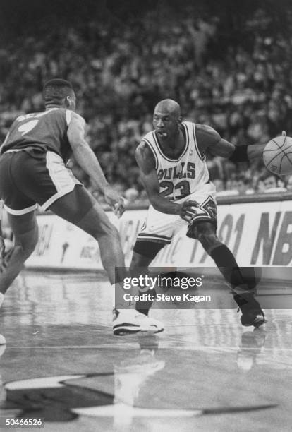 Chicago Bulls' star Michael Jordan furiously dribbling ball around opponent in NBA championship basketball game between the Bulls & the L.A. Lakers...