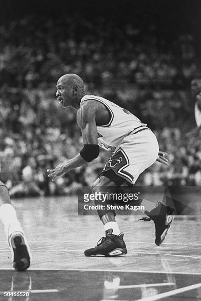 Chicago Bulls' star Michael Jordan crouching in order to guard approaching unseen opponent during NBA championship basketball game between the Bulls...