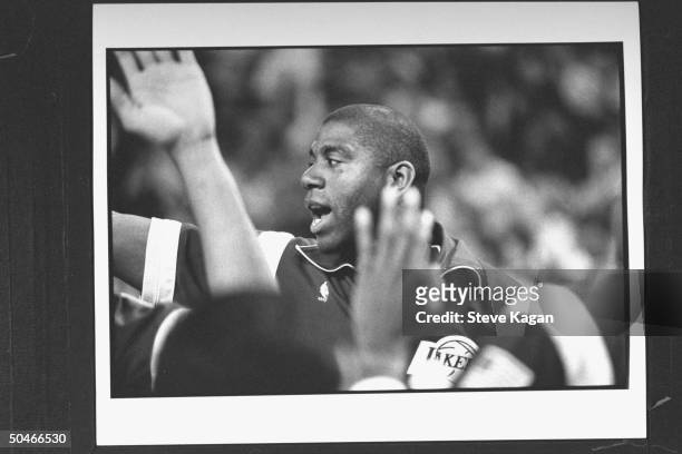 Lakers' star Magic Johnson yelling as he gives high-five in midst of several hands of unseen teammates before the start of NBA championship...
