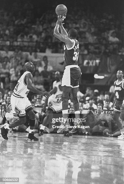 Lakers' star Magic Johnson making a jump shot as Chicago Bulls' star Michael Jordan rushes in to block it during NBA championship game at Chicago...