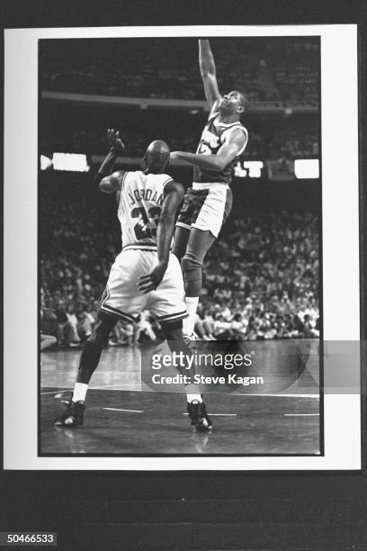 Lakers' star Magic Johnson making a jump shot as Chicago Bulls' star Michael Jordan starts to block it during NBA championship game at Chicago...