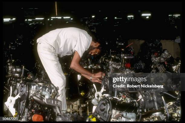 Worker examining engines at Maruti govt-owned car mfg. Co., re joint venture w. Ford Motors US co. & efforts to improve performance of state...