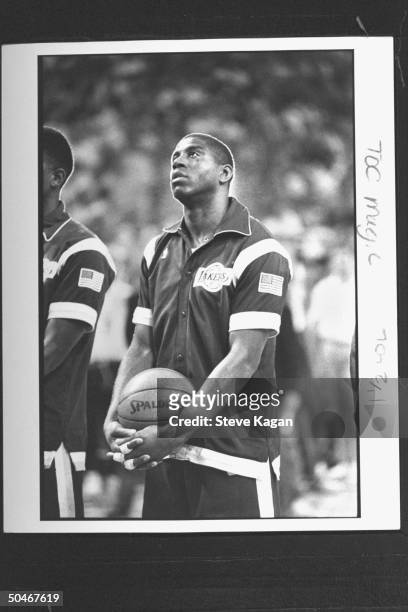 Lakers' star Magic Johnson holding basketball as he stands in his warmup suit during the playing of the national anthem at NBA championship...