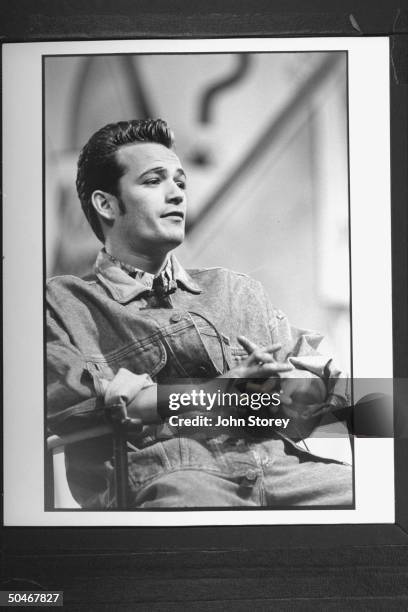 Actor Luke Perry sitting in chair during interview after fashion show.