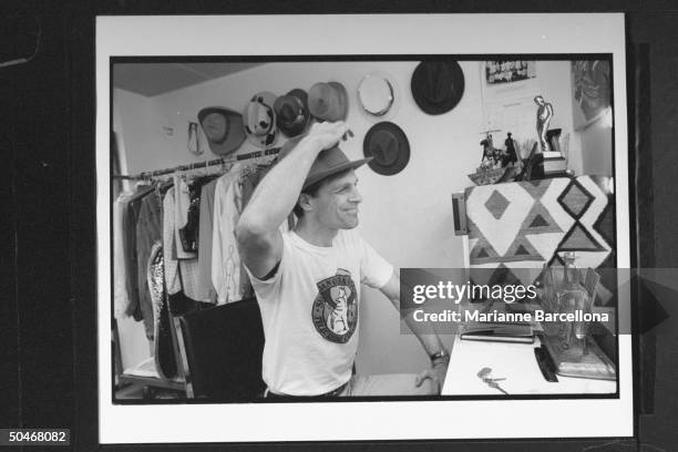 Actor Keith Carradine putting on hat as he sits before mirror in his dressing room at the Palace Theater where he is starring in the musical The Will...