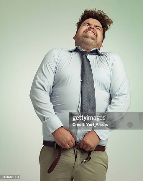 willing his pants closed - buttoning shirt stockfoto's en -beelden