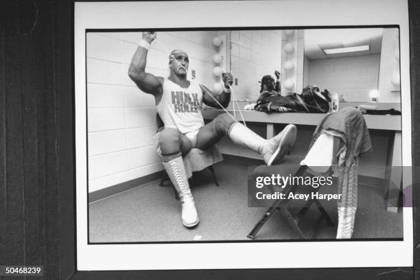 Wrestler Hulk Hogan in his wrestling togs, lacing up hightop boots as he sits in dressing room before his bout at the Miami Arena.