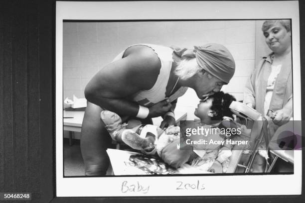 Wrestler Hulk Hogan tenderly kissing the forehead of wheelchair-bound, disabled 4-yr-old Porche Duff, one of Hogan's biggest admirers, in his...