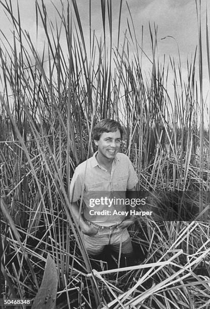 Newspaper columnist & author Carl Hiaasen standing in water & sawgrass.