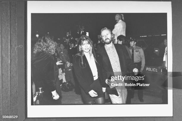 Actor Linda Hamilton w. Movie dir. James Cameron dashing past photographers outside Planet Hollywood restaurant as they arrive at opening party.