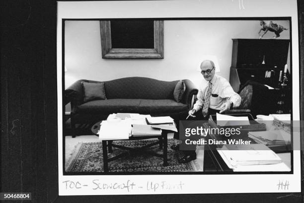 Adv. Brent Scowcroft in shirt-sleeves, going over some papers as he sits at coffee table next to large desk in his commodious office at the WH late...