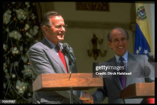 Pres. Bush w. Pres. Carlos Andres Perez shaking hands, poised at twin podiums during news conf. Outside pres. Palace in Caracas, Venezuela.