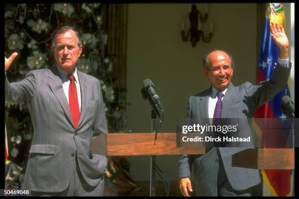 Pres. Bush w. Pres. Carlos Andres Perez poised waving, at twin podiums during news conf. Outside pres. Palace in Caracas, Venezuela.