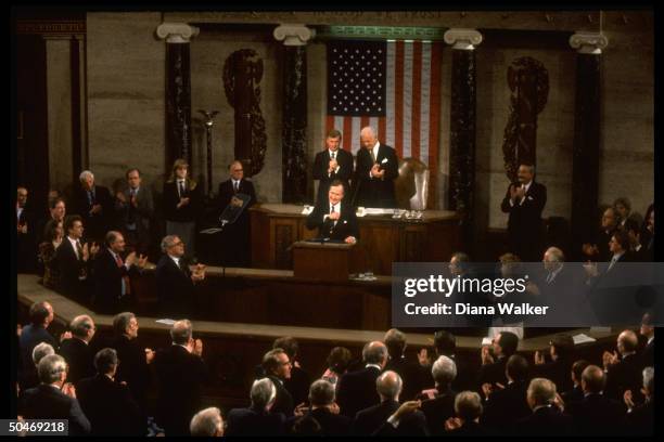 Overview of Joint Session of Congress applauding Pres. Bush after his speech, framed by House Spkr. Tom Foley , VP Dan Quayle & flag backdrop.