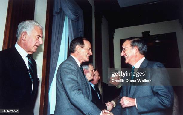 Pres. Bush shaking hands w. Sen. Maj. Ldr. George Mitchell , all smiles, paying St. Patrick's Day call on Capitol Hill, w. House Spkr. Tom Foley .