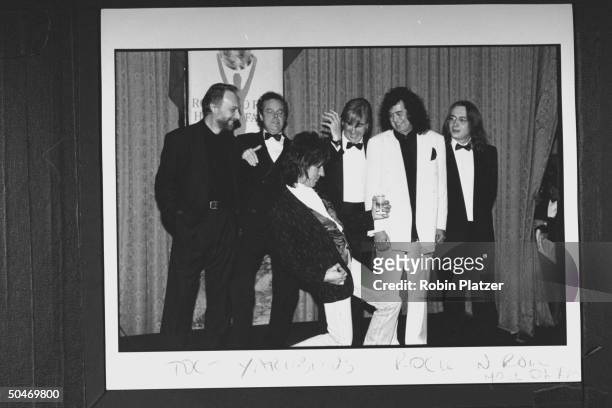 Rock guitarists Jimmy Page & Jeff Beck who is pantomime strumming a riff on a guitar while holding drink as several unident. Members of rock group...