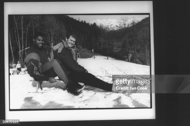 Blobsled teammates , football star Herschel Walker & ex-skier Randy Will, sitting together on small sled on practice slope as they relax from...