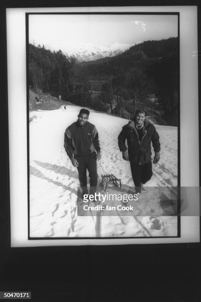 Blobsled teammates , football star Herschel Walker & ex-skier Randy Will, pulling a small sled up practice slope as they relax from training for...