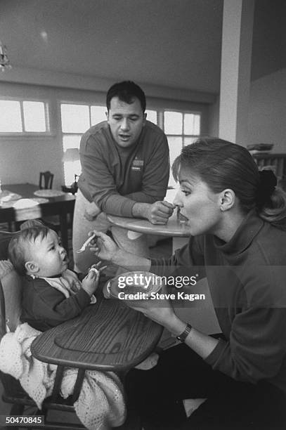 Ice skating commentator for the Winter Olympics, former ice dancer Tracy Wilson spoon feeding her baby son Shane as he sits in high chair as her...