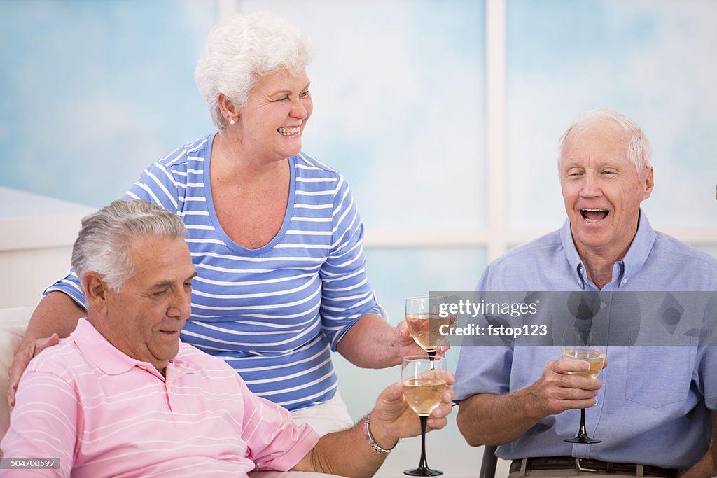 Senior adult friends share news, friendship.  Wine. Home setting.