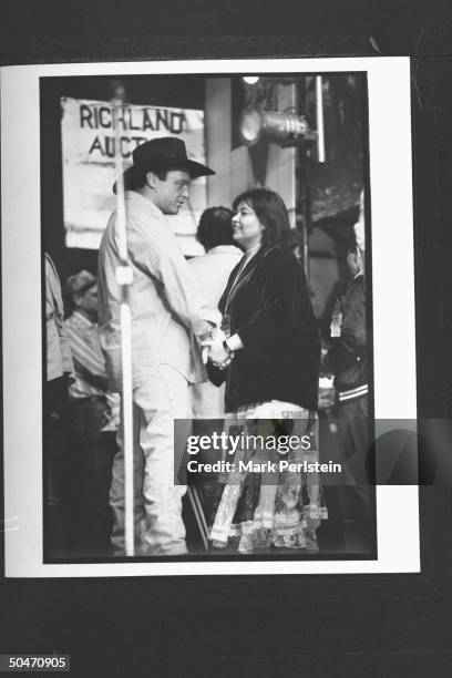 Comedian Tom Arnold w. Actress/comedienne wife Roseanne holding hands backstage during the Farm Aid V concert at Texas Stadium.