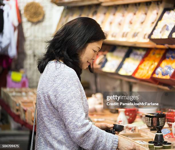 asian woman shopping for tea set at outdoor market - temple street market stock pictures, royalty-free photos & images