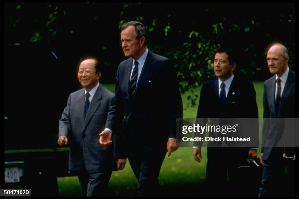 Pres. Bush & Japanese PM Kiichi Miyazawa treading WH lawn, leaving for Camp David, w. NSC Adviser Brent Scowcroft & unident. Aide in tow.