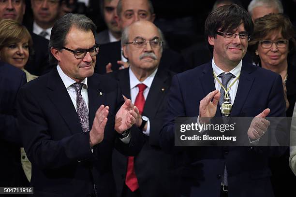 Carles Puigdemont, Catalonia's incoming president, right, and Artur Mas, former Catalan acting president, left, applaud during the swearing in...