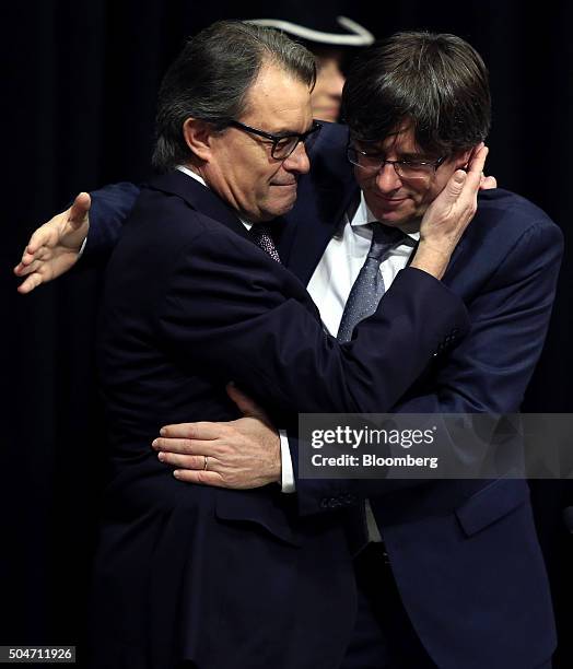 Carles Puigdemont, Catalonia's incoming president, right, embraces Artur Mas, former Catalan acting president, after he is sworn into office at the...