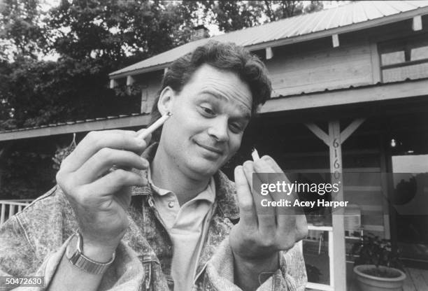 Singer Doug Stone breaking cigarette in half in symbolic gesture of breaking the smoking habit, to which he & his doctors attribute part of his heart...