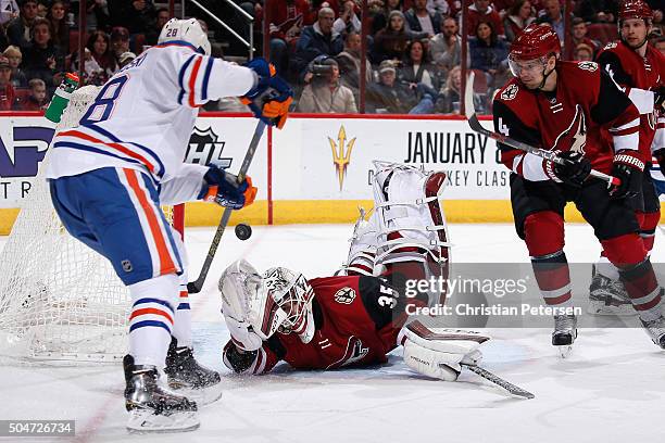 Goaltender Louis Domingue of the Arizona Coyotes makes a diving save on a shot as Lauri Korpikoski of the Edmonton Oilers looks for a rebound during...