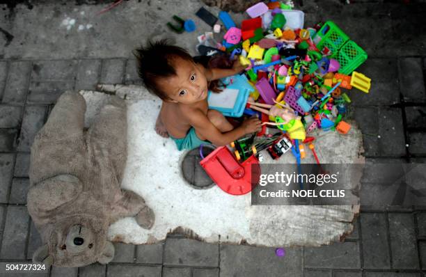 Homeless boy plays with different toys collected by his parents that picks used plastic soda bottles to sell at junk shops in Manila on January 13,...