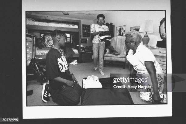 Mack Daddy , member of rap duo Kris Kross, kneeling on floor in front of open suitcase as his mom Donna brings him clothes to pack for his current...