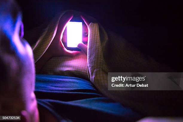 man checking smartphone at late night inside bed with bright light from point of view. nomophobia. vibranxiety, ringxiety and fauxcellarm. - staring at screen stock pictures, royalty-free photos & images