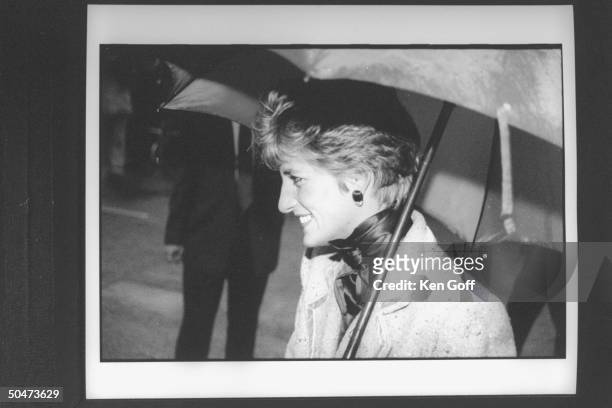 Princess Diana clad in double-breasted wool suit, carrying an open umbrella, during her walking tour in the rain. North England.