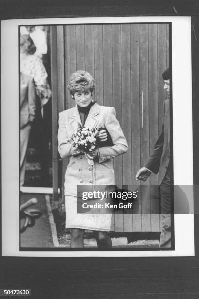 Princess Diana clad in double-breasted wool suit, carrying small bouquet of flowers outside w. Bodyguard nearby during walking tour. North England.
