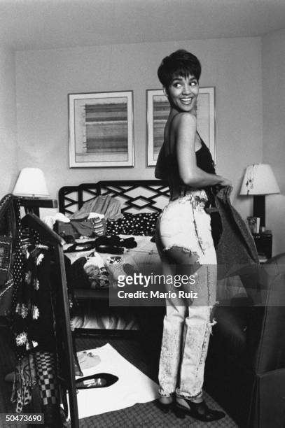 Actress Halle Berry in black brassiere & ripped jeans featuring revealingly strategic holes at hip & knee, trying on outfits in cluttered bedroom of...