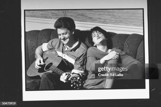 Ex-child actress Claudia Lamb, now a radio talk-show host, singing as her husband Scott Augusto accompanies her on guitar while sitting on couch at...